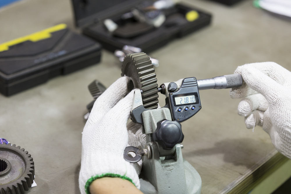 Technician in gloves uses a tool to measure a gear's spur size