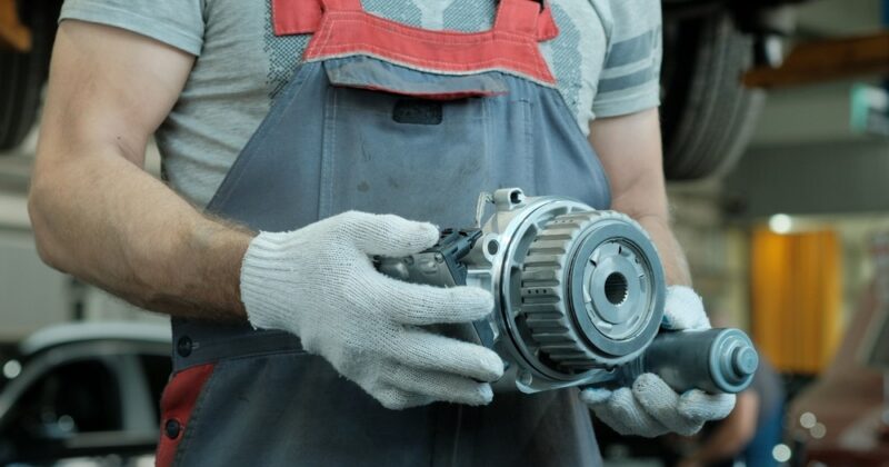 Technician in gloves holds a faulty gearbox with gear reducers.