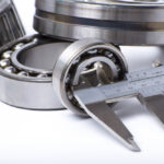 Close up of industrial bearings with measuring tool on white background