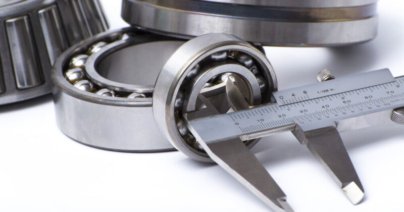Close up of industrial bearings with measuring tool on white background