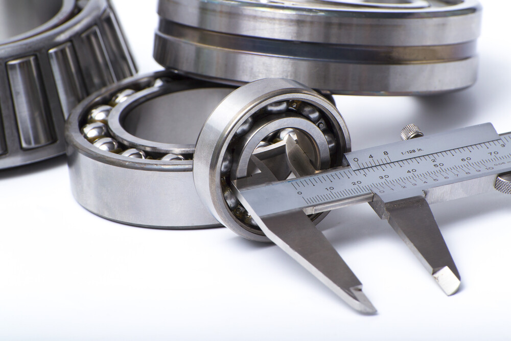 Close up of industrial bearings with measuring tool on white background